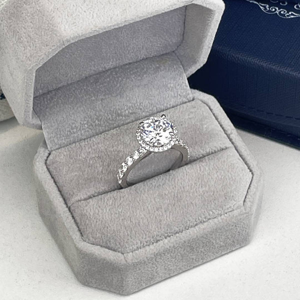 3ct round lab diamond cathedral style engagment ring with 3ct round diamond framed by a halo of small diamonds. a diamond pave set cathedral style band supports the 3ct centre diamond.