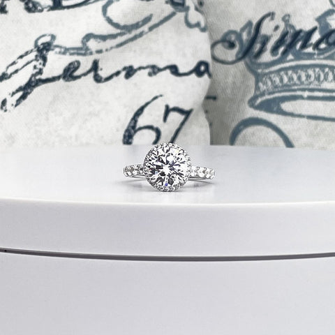 14K white gold engagement ring with 3ct round diamond, framed by a halo of smaller diamonds, on a band of pave set round cut diamonds.