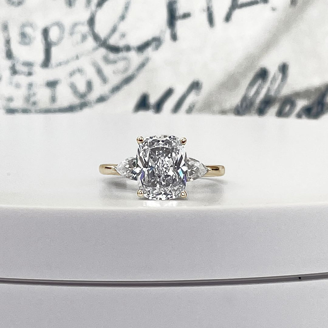 A 3ct Cushion cut diamond with two 0.50ct pear side stones on a 14k yellow gold engagment ring.