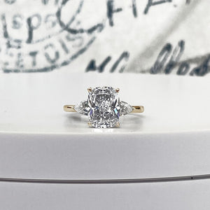 A 3ct Cushion cut diamond with two 0.50ct pear side stones on a 14k yellow gold engagment ring.