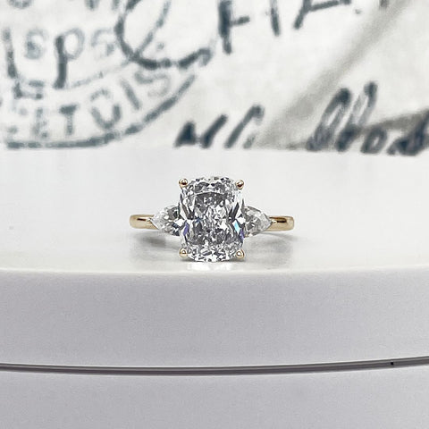 A 3ct Cushion cut diamond with two 0.50ct pear side stones on a 14k yellow gold engagment ring.