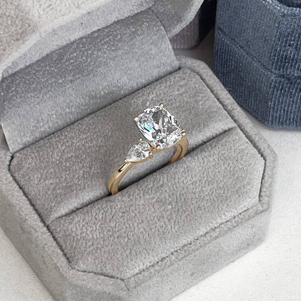 a 3 carat cushion cut diamond engagement ring with two 0.50ct pear side diamonds in 14k yellow gold.